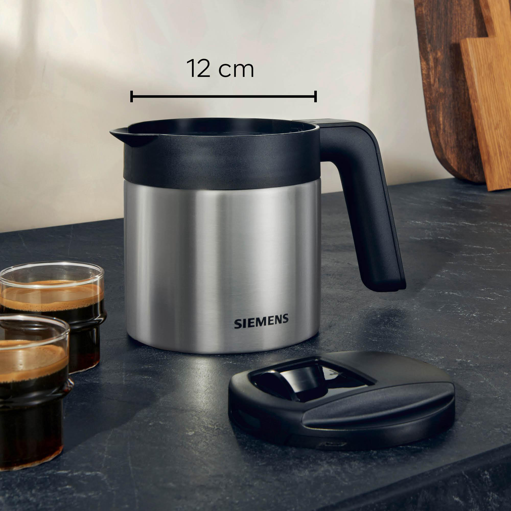 Kaffeekanne aus Edelstahl mit schwarzem Griff und Deckel. Zwei Espressogläser.