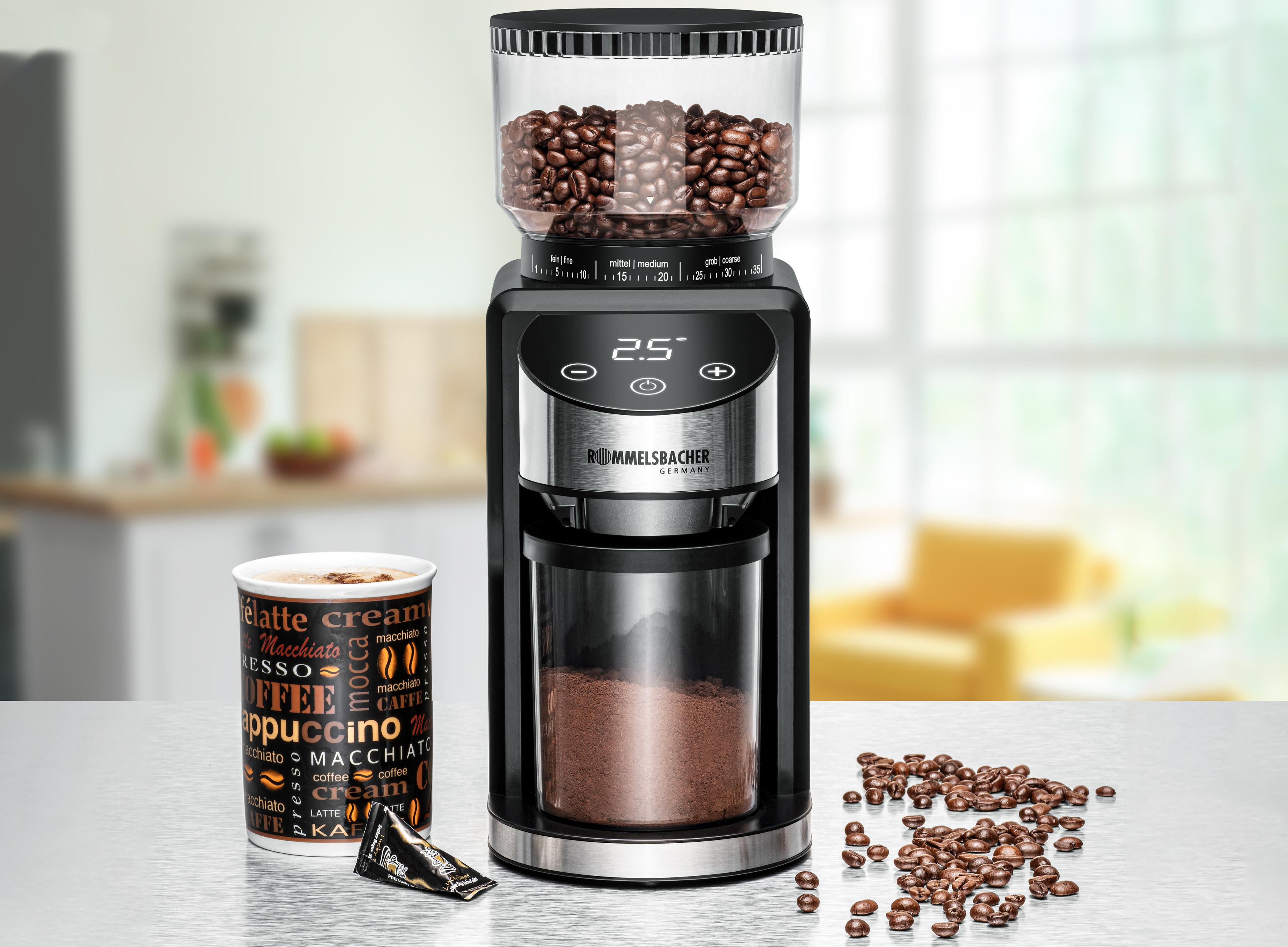 Kaffeemühle mit Bohnen oben, gemahlener Kaffee unten. Tasse Kaffee und Bohnen daneben.