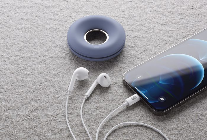 Écouteurs et un étui de chargement sur une surface en pierre à côté d'un smartphone.