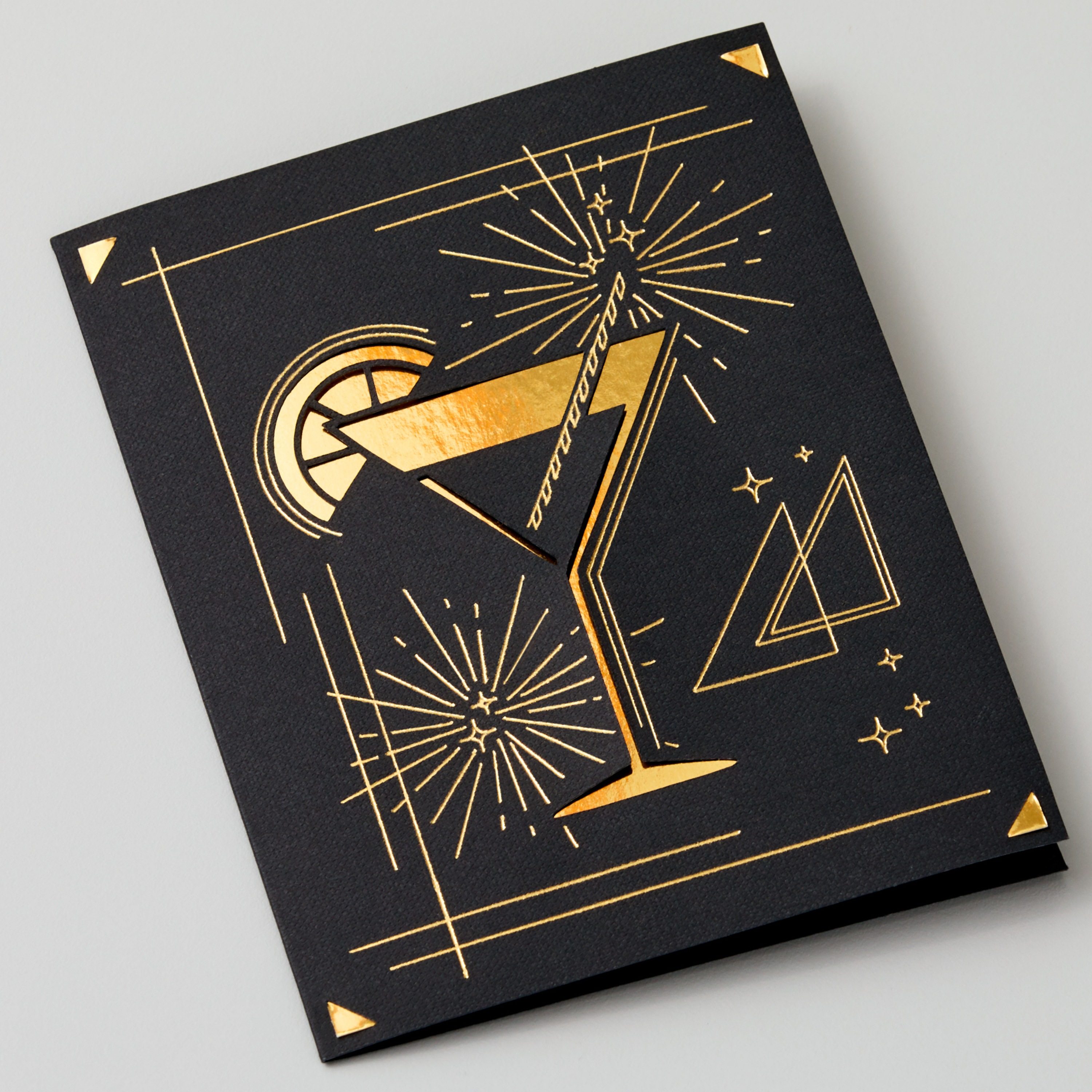 Eine schwarze Karte mit einem goldenen Cocktail-Design darauf.
