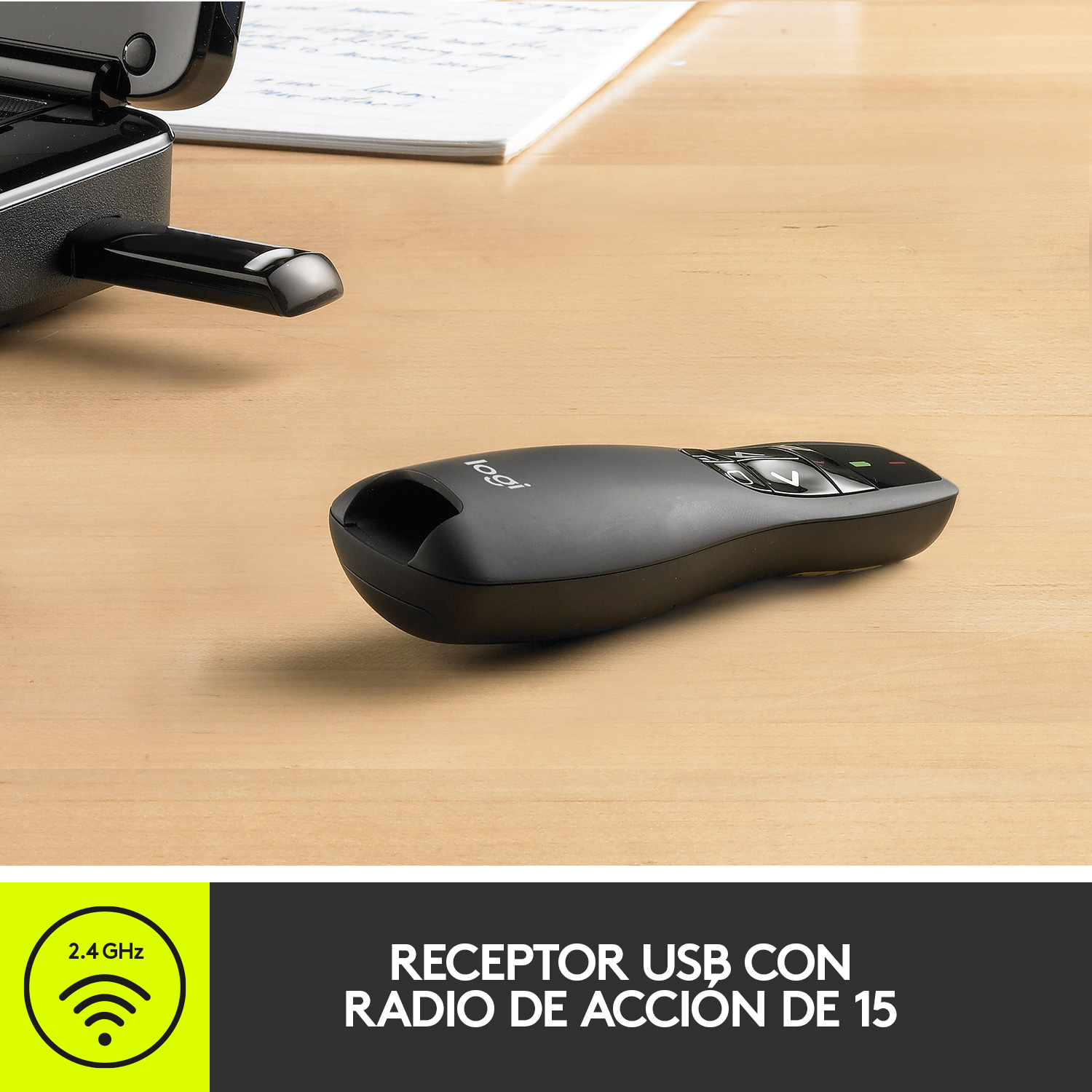 Un mando a distancia de presentación Logitech negro sobre un escritorio de madera junto a un portátil.