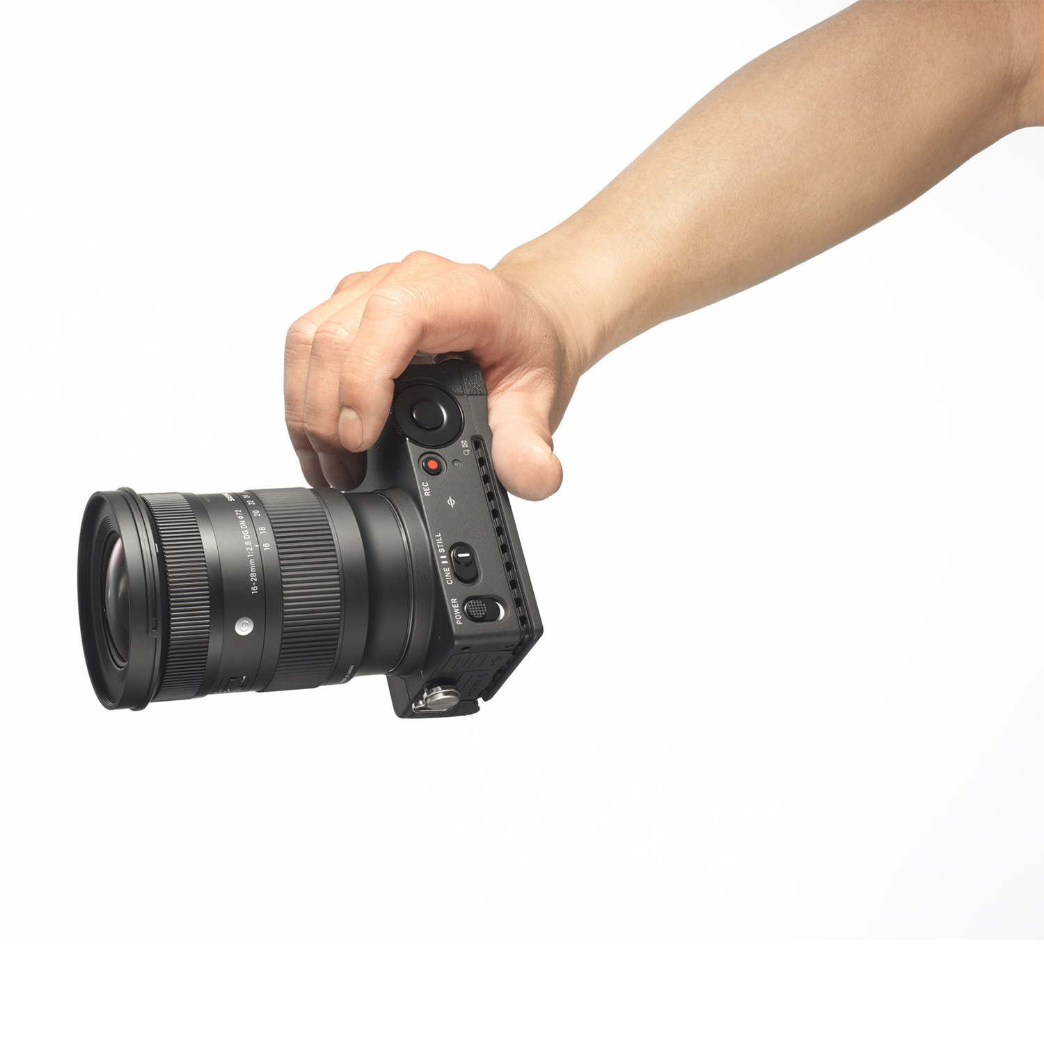 Una mano che tiene una fotocamera Sigma con un obiettivo, contro uno sfondo bianco.
