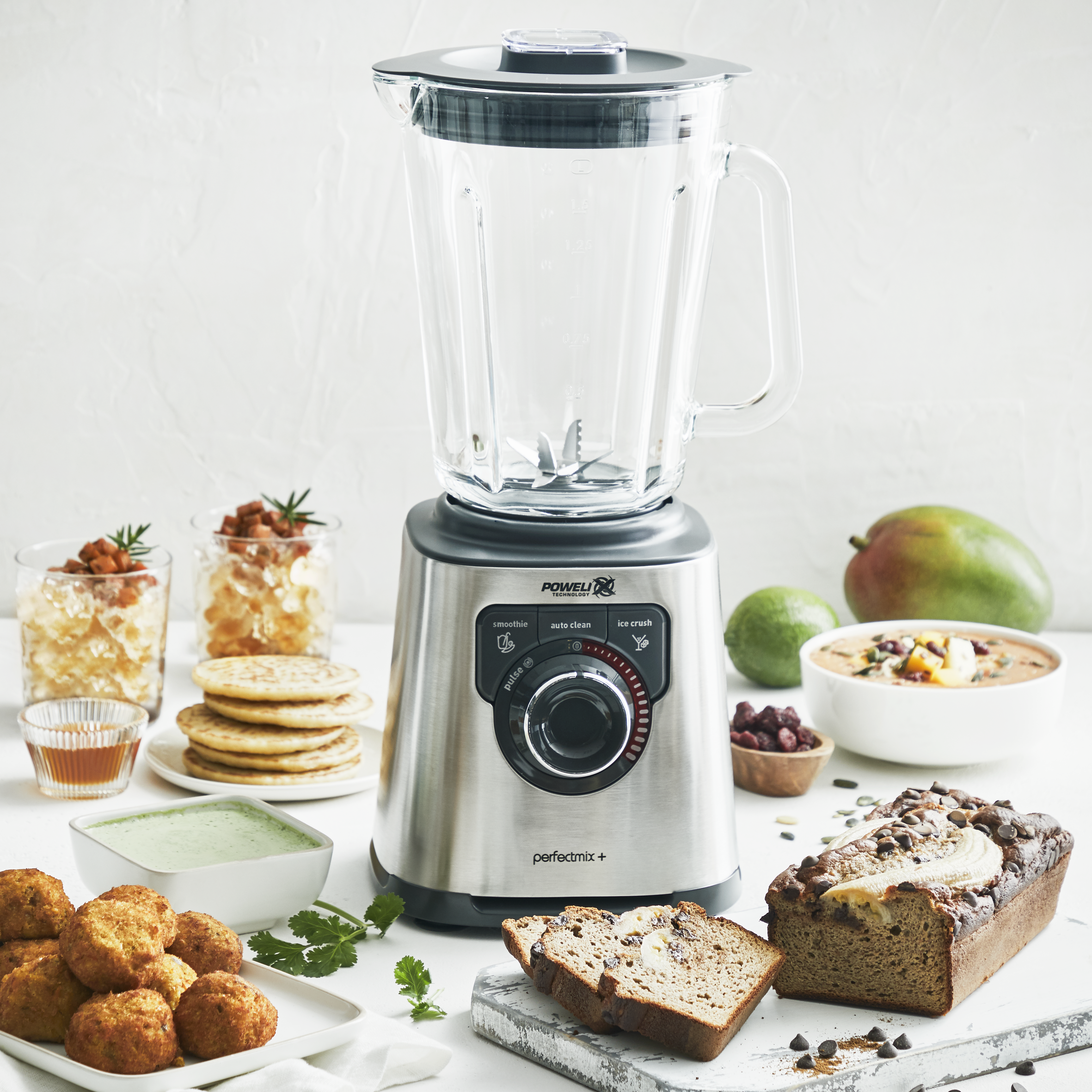 Licuadora con ingredientes alrededor, incluyendo fruta y productos horneados.