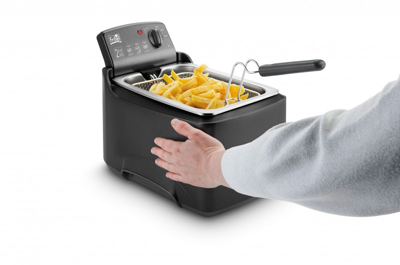 Een zwarte friteuse met friet in de mand en een hand die ernaar grijpt.