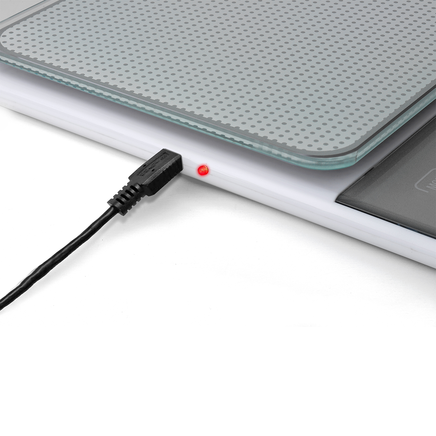Bilancia bianca con cavo USB nero collegato, che mostra una luce rossa, con piano in vetro.