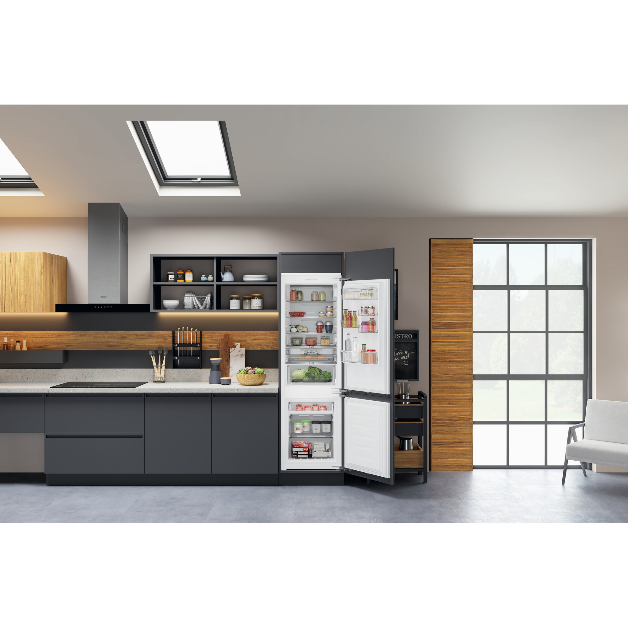 Moderne Küche mit offenem Kühlschrank, der Lebensmittel zeigt. Graue Schränke, Fenster und Oberlicht.