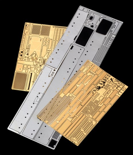 Mehrere Metallplatten mit geätzten Mustern auf schwarzem Hintergrund.
