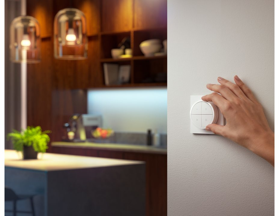 Une main ajustant un variateur de lumière intelligent blanc.
