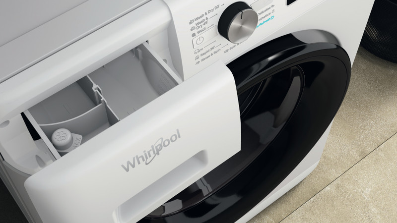 Fehér Whirlpool mosógép fiók nyitva. Mosószer és öblítő rekeszeket tartalmaz. Fekete-fehér részlet.