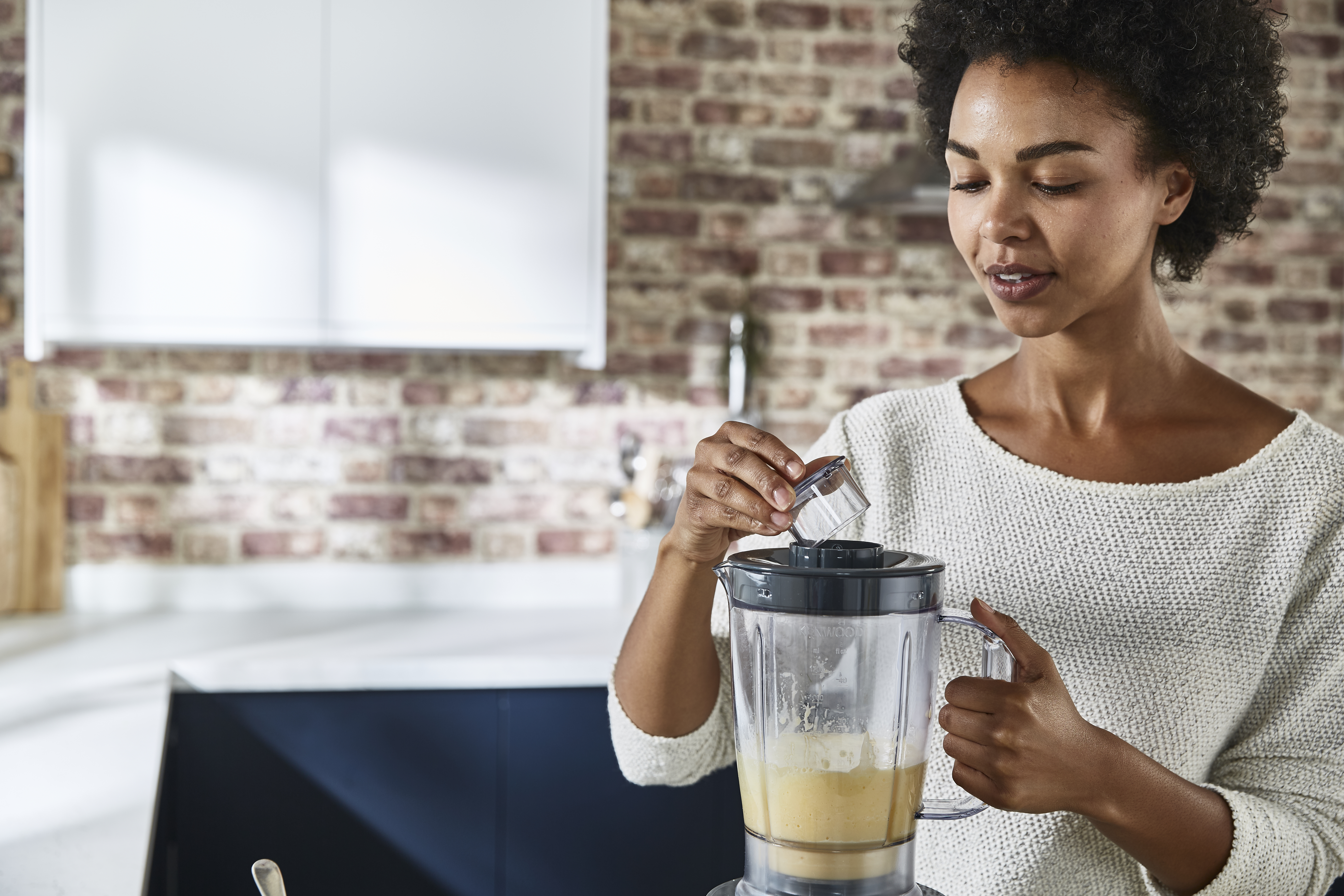 Woman adding ingredients to a blender.
