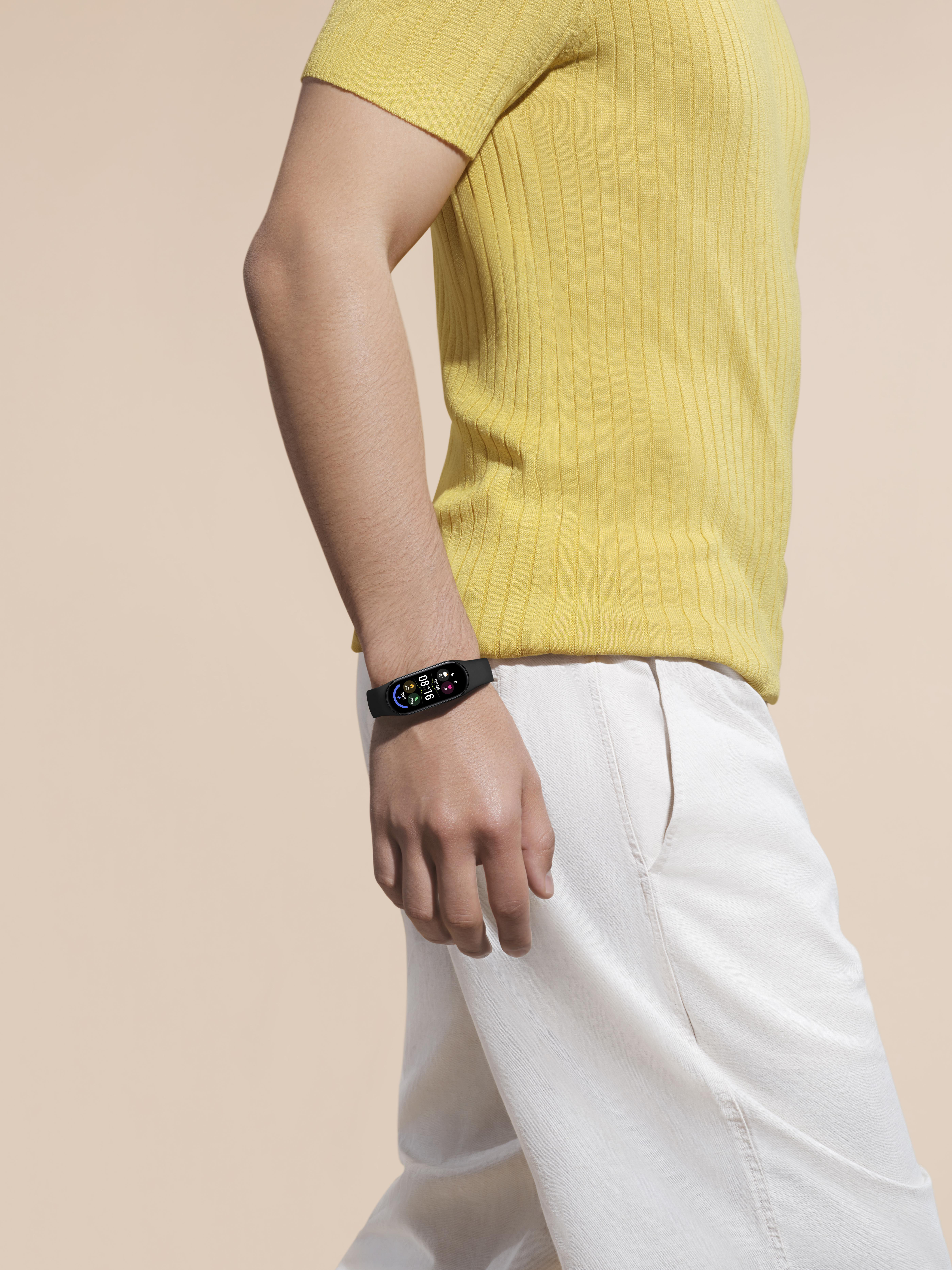 Eine Person trägt ein gelbes Hemd und eine weiße Hose. Eine Smartwatch ist am Handgelenk.
