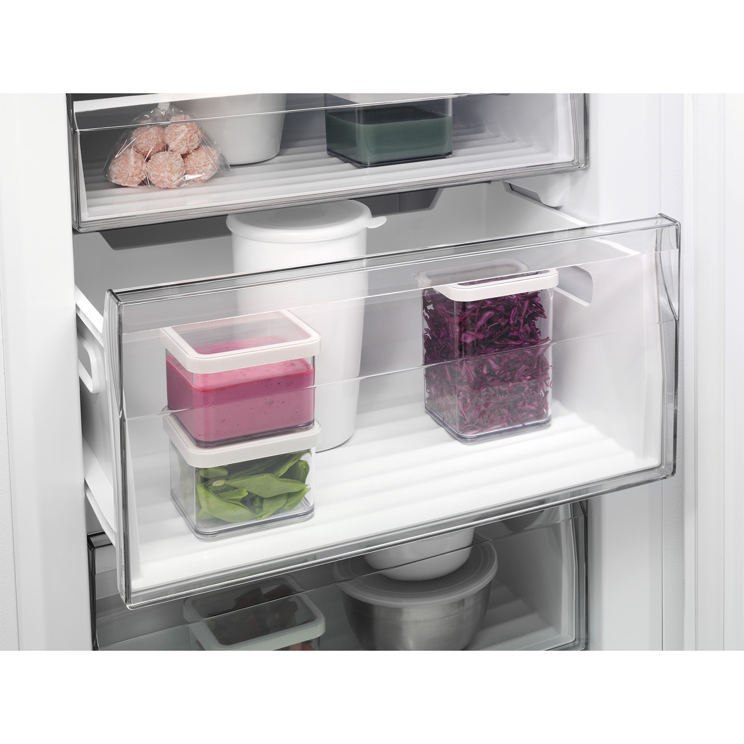 Interno del frigorifero con cassetti e contenitori. Contiene alimenti come verdure e surgelati.