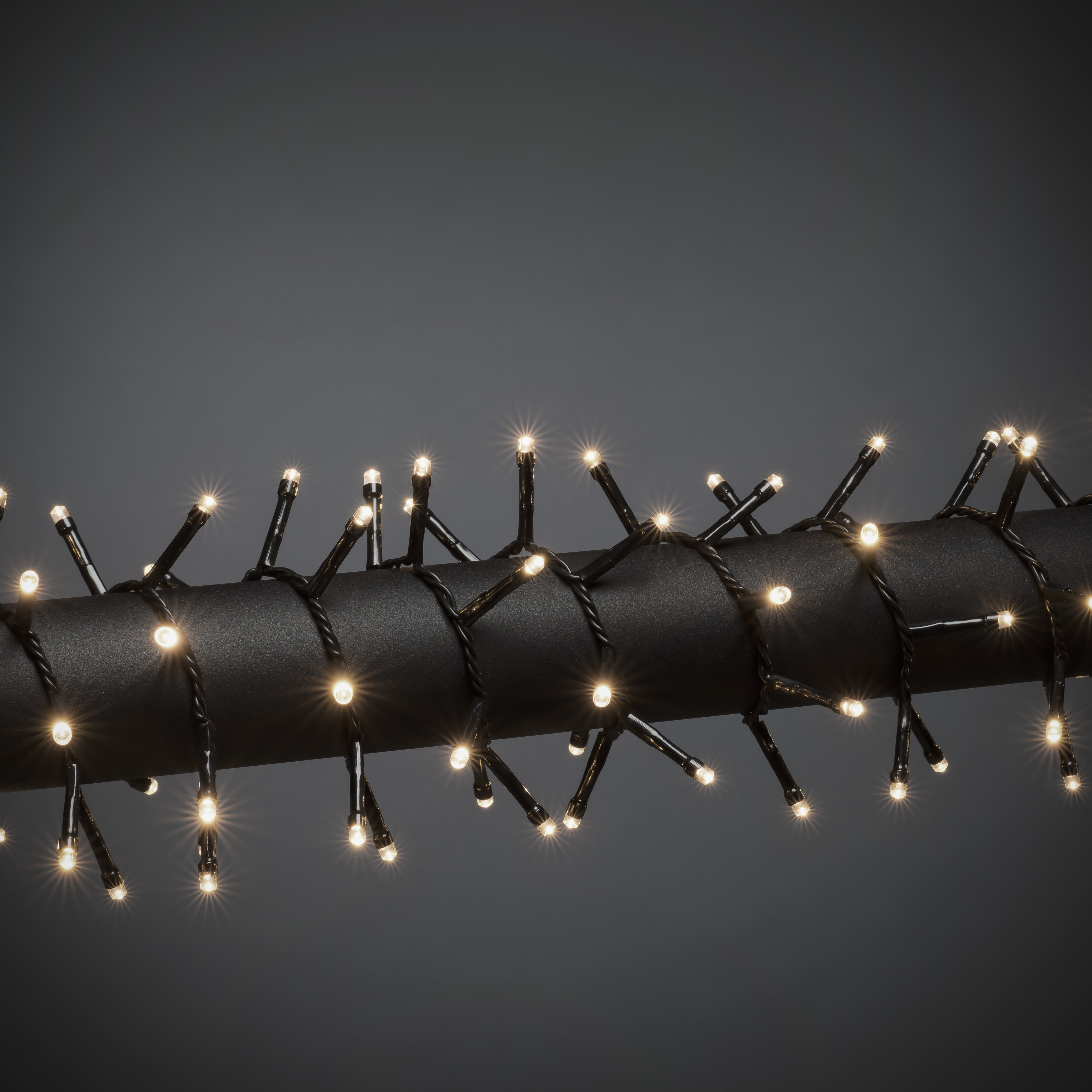 Eine Lichterkette auf dunkler Oberfläche. Die Lichter leuchten, der Hintergrund ist dunkelgrau.