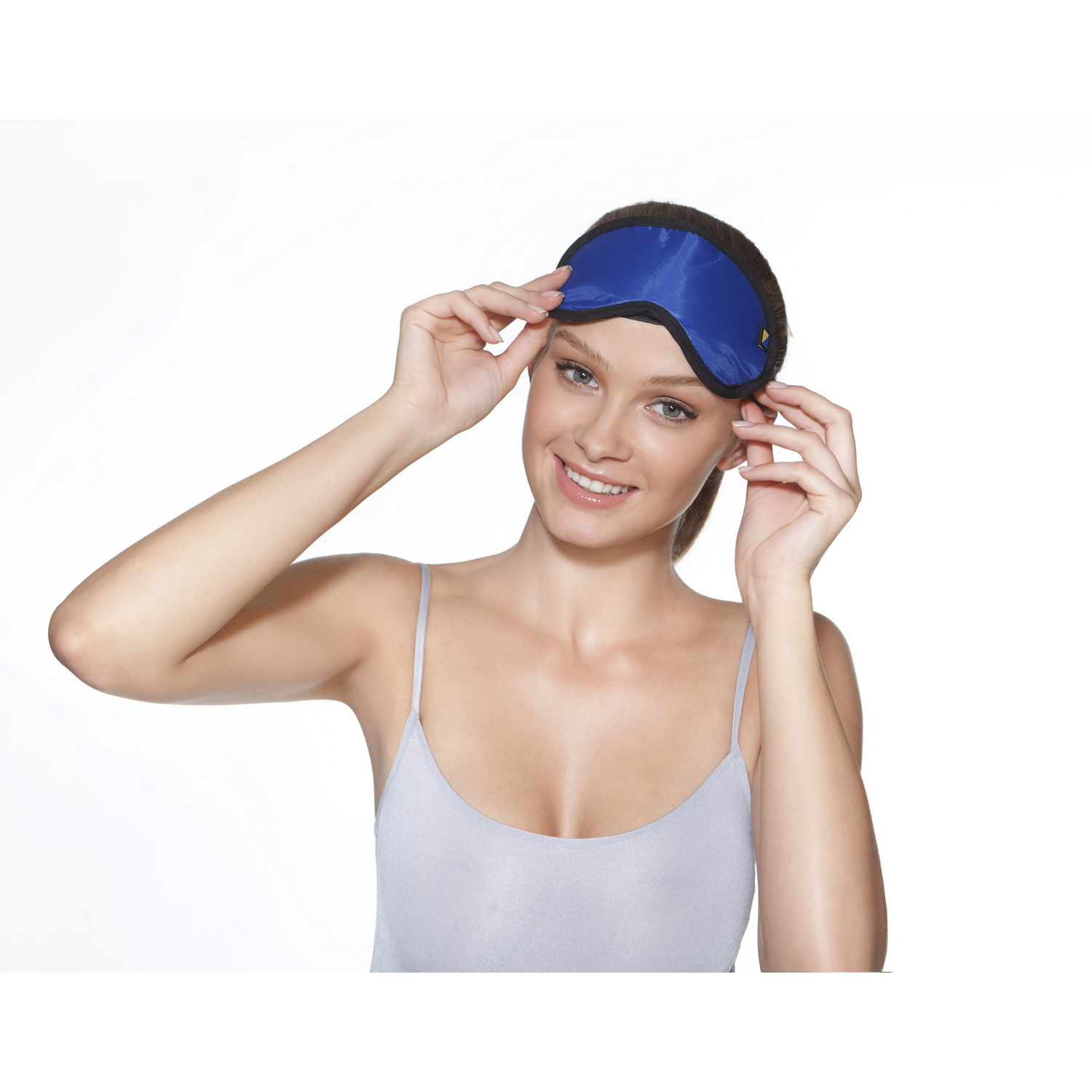Mujer sosteniendo una máscara azul para los ojos. Sonríe, fondo blanco.