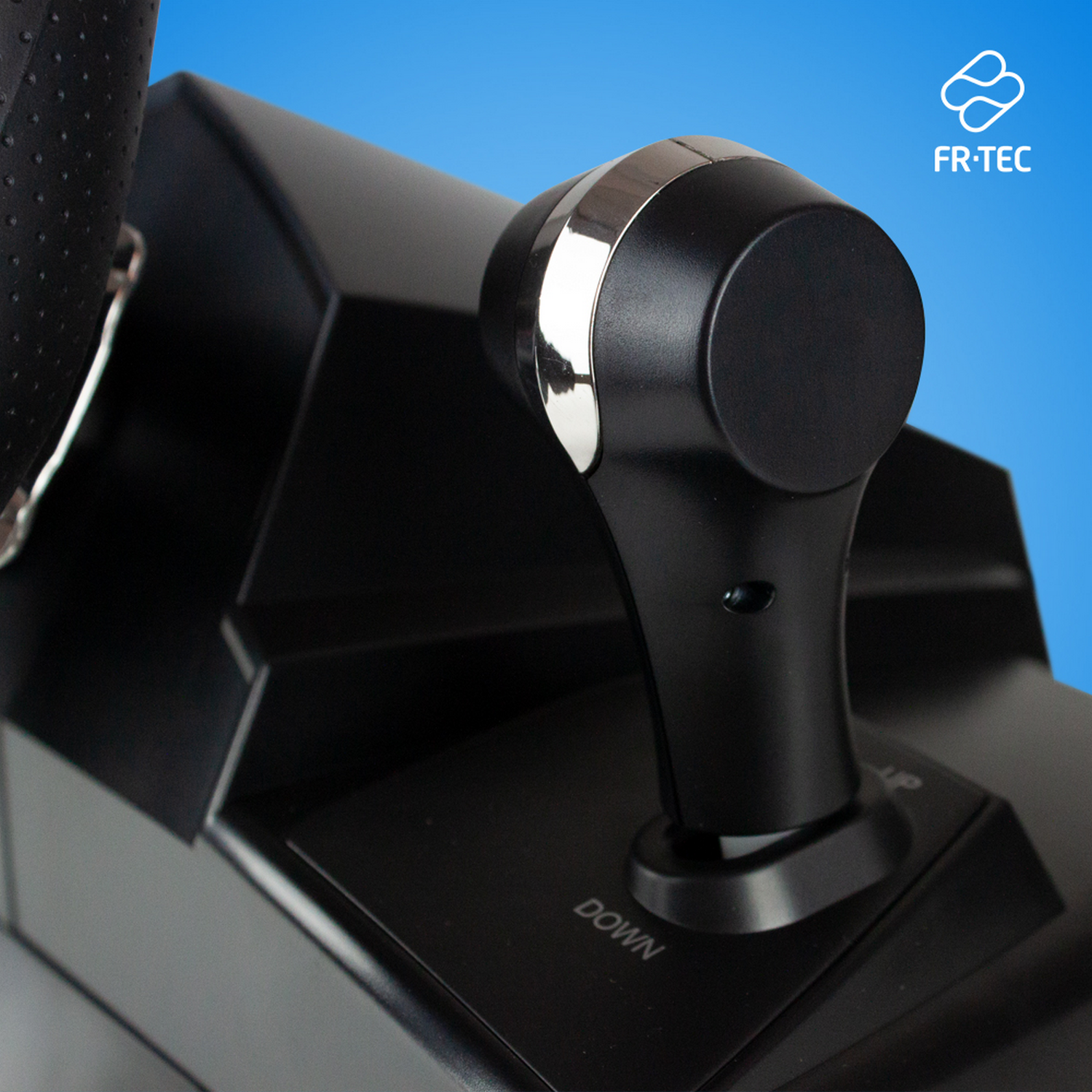 Joystick de juego negro con parte superior plateada. El fondo es azul con el logo de FR-TEC.