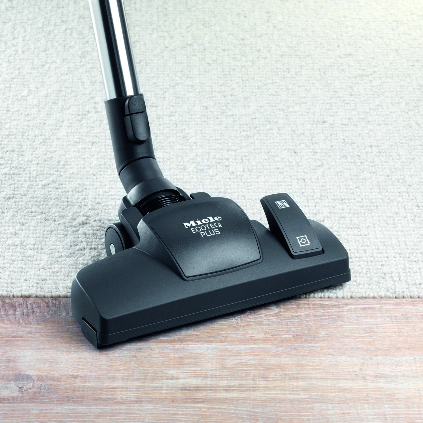 Close-up of a black vacuum cleaner head on a light-colored rug, with the brand name visible.