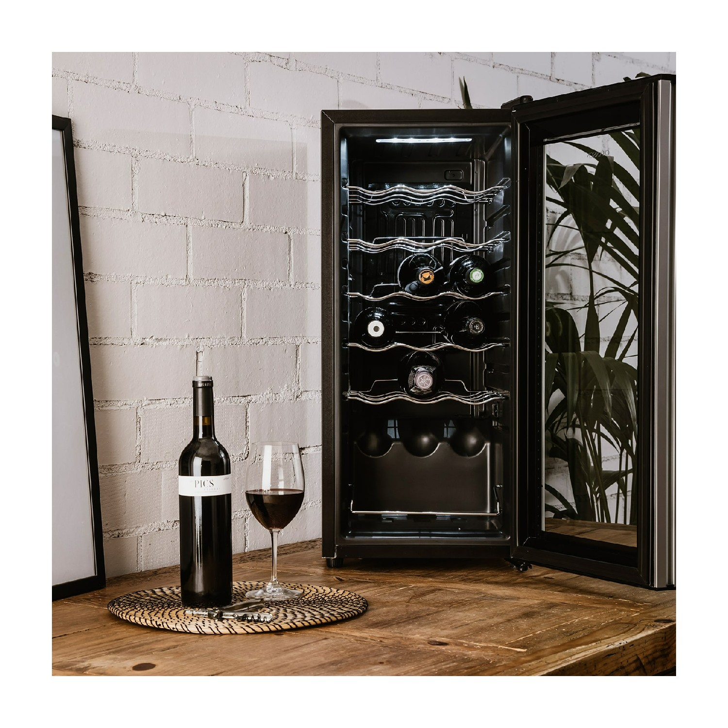 Una vinoteca con una botella de vino y una copa sobre una mesa de madera.