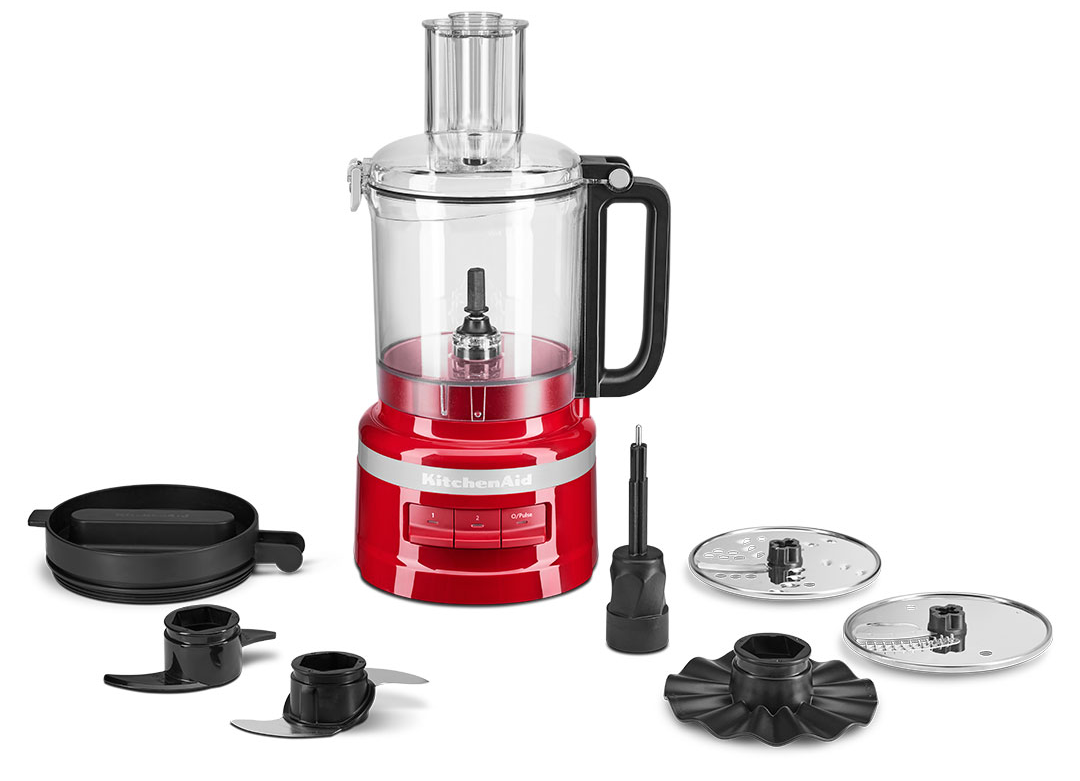 Piros KitchenAid konyhai robotgép tartozékokkal: pengék, tál és fedél. Piros szín és fehér háttér.
