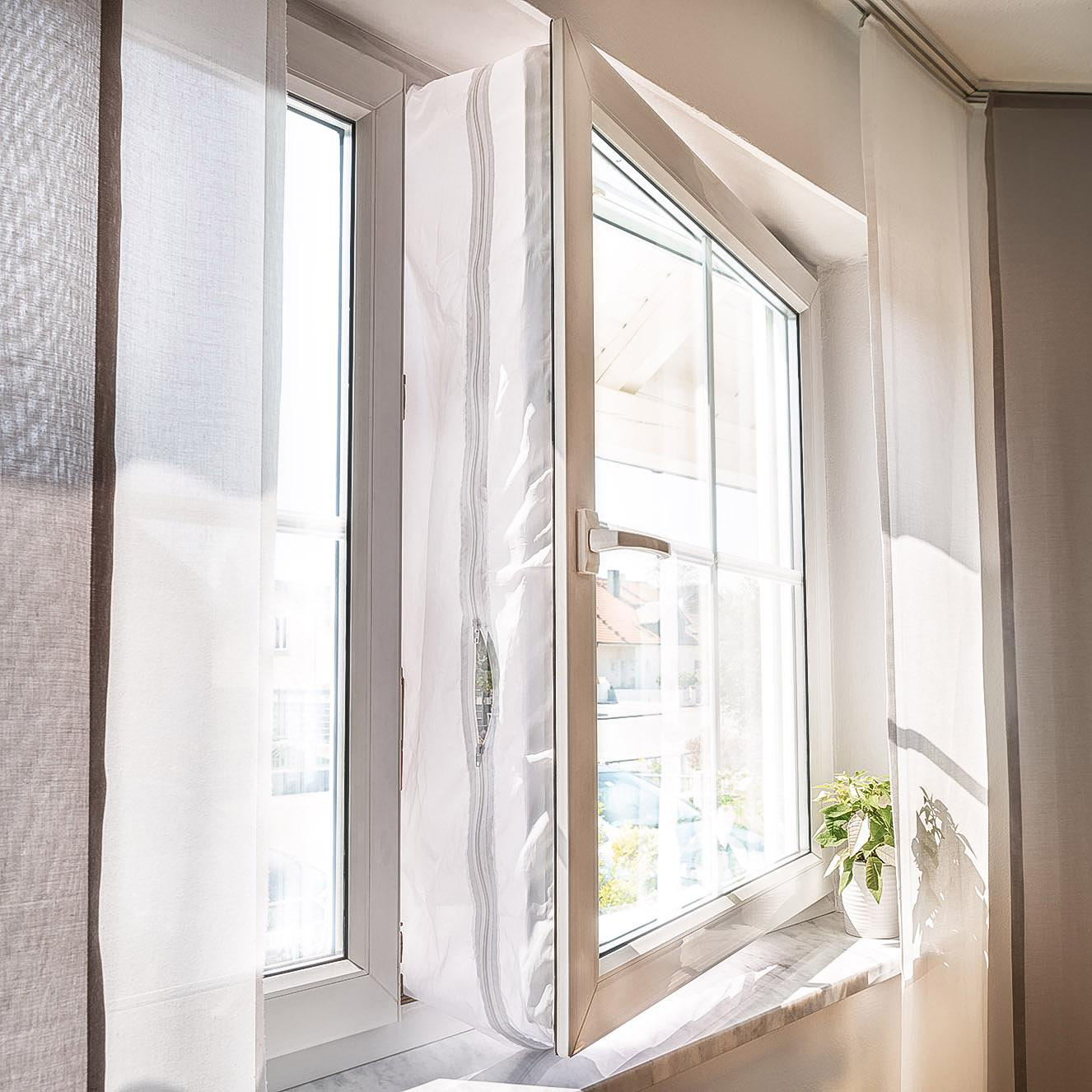 Ein offenes Fenster mit transparenten weißen Vorhängen und einer kleinen Pflanze.