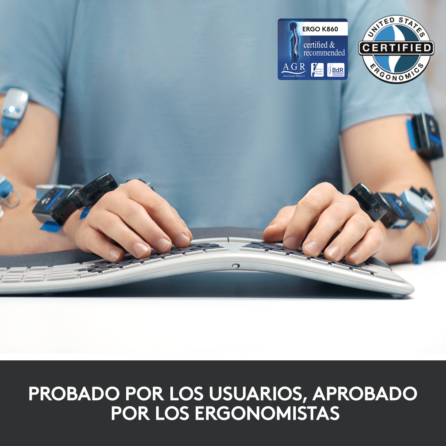 Manos de un hombre con dispositivos de monitoreo en los brazos, escribiendo en un teclado curvado.