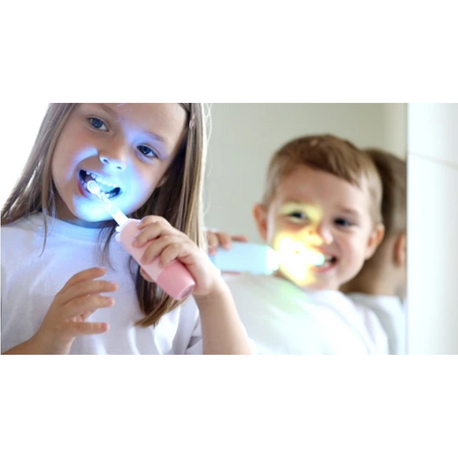 Dos niños cepillándose los dientes con cepillos de dientes brillantes frente a un espejo.
