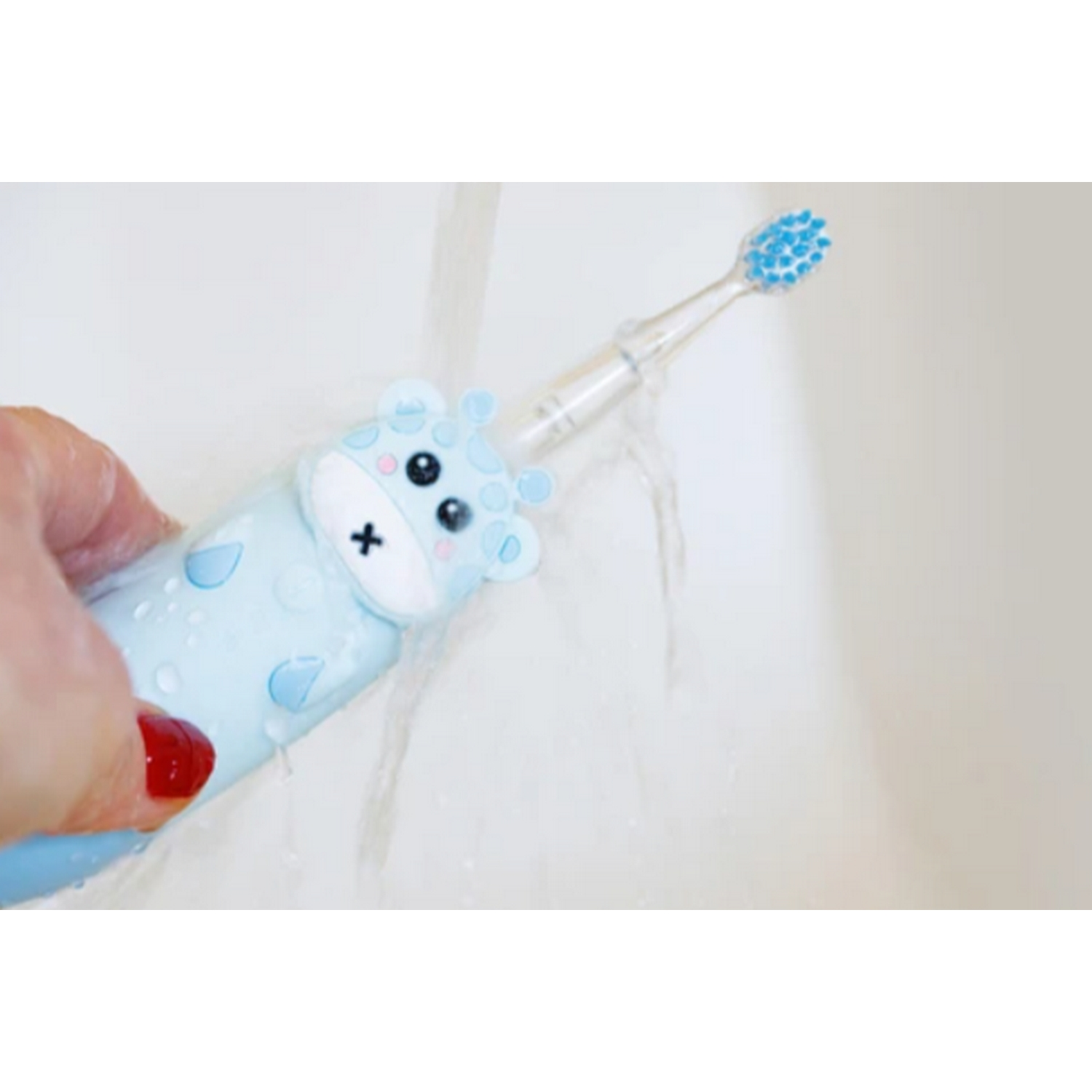 Un cepillo de dientes de jirafa azul bebé está bajo el agua corriente en el fregadero.