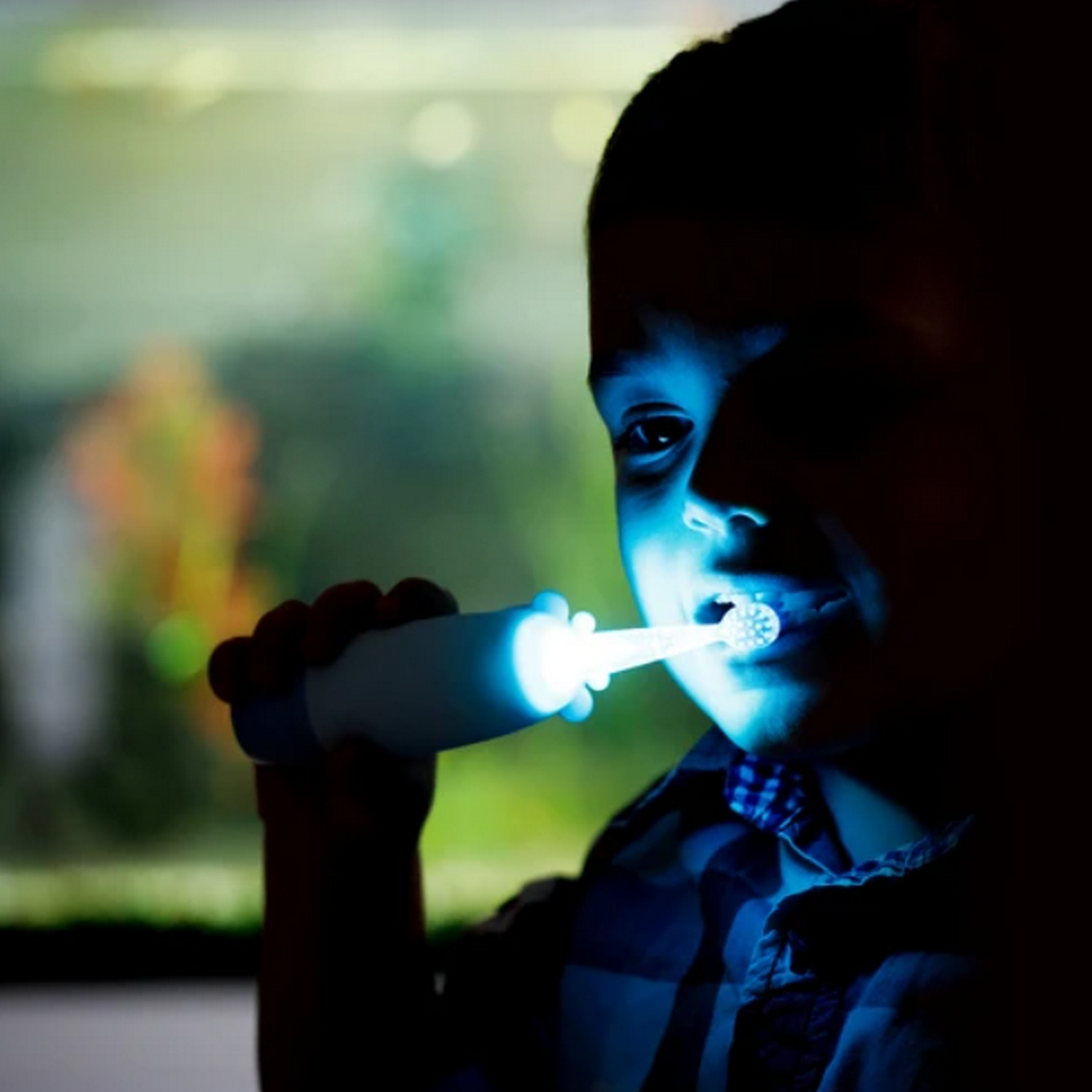 Un niño cepillándose los dientes con un cepillo de dientes azul brillante.