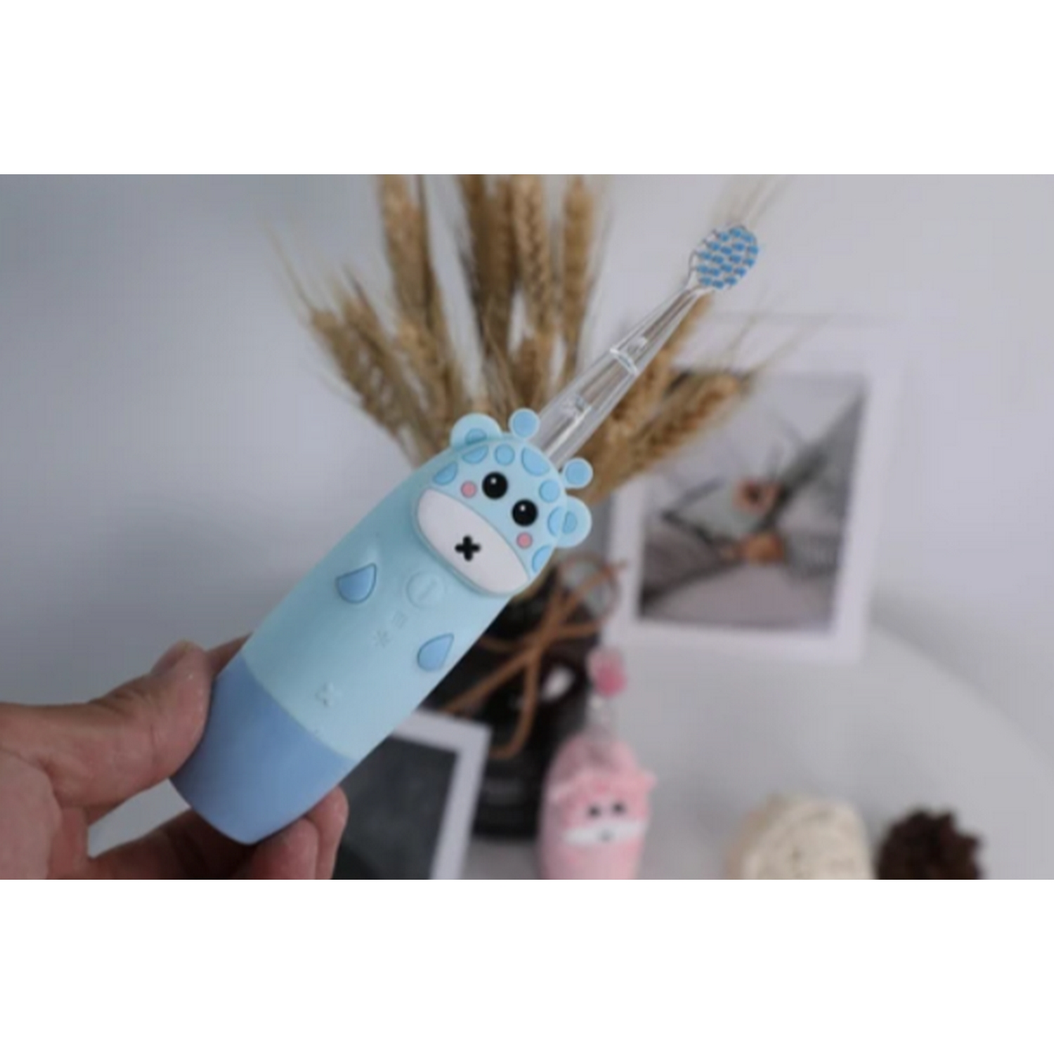 Un cepillo de dientes azul y blanco con tema de jirafa sostenido por una mano.