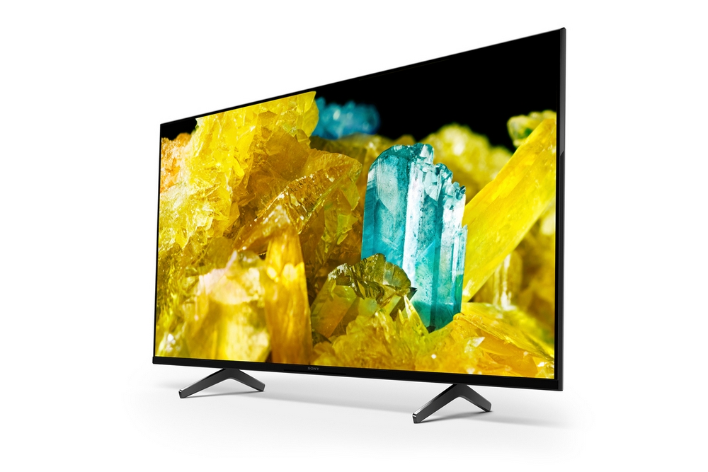 Televisor con pantalla vibrante que muestra cristales coloridos. Soporte negro y fondo blanco.