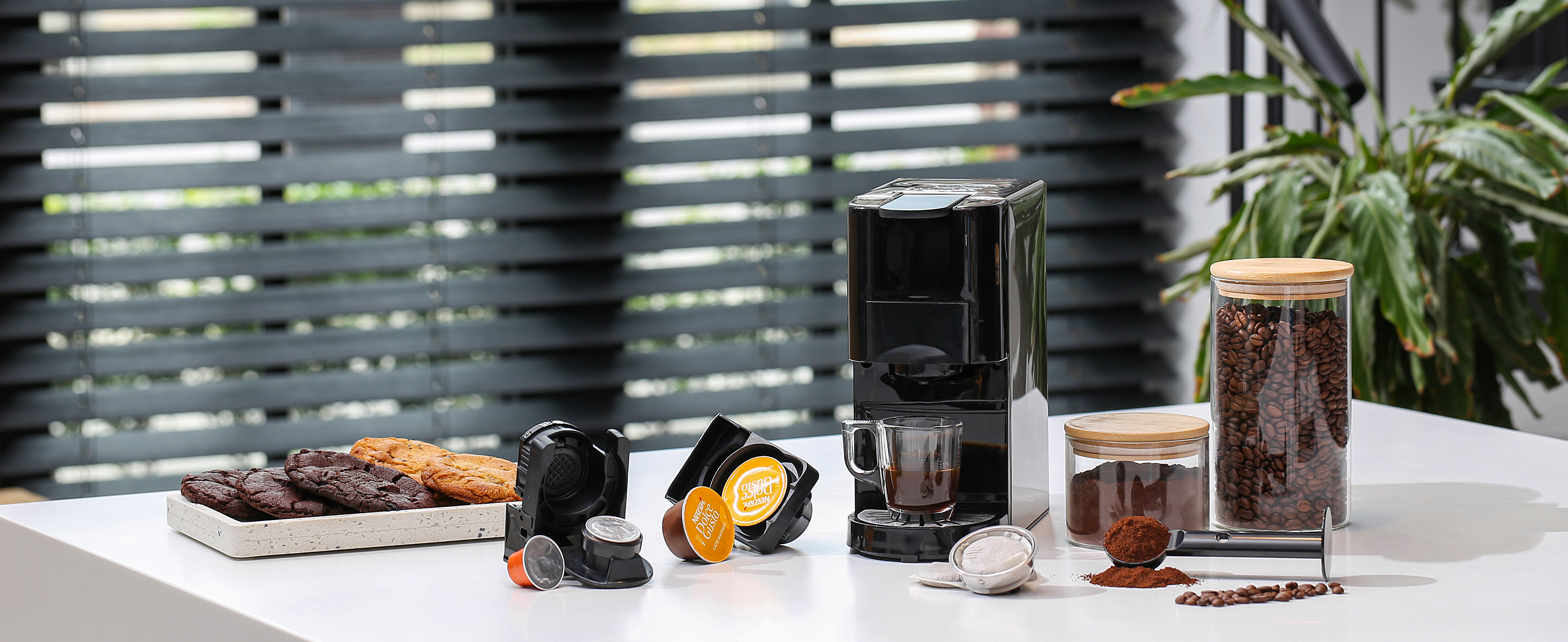 Koffiemachine met koffieaccessoires. Koffiebonen, kopjes en koekjes.