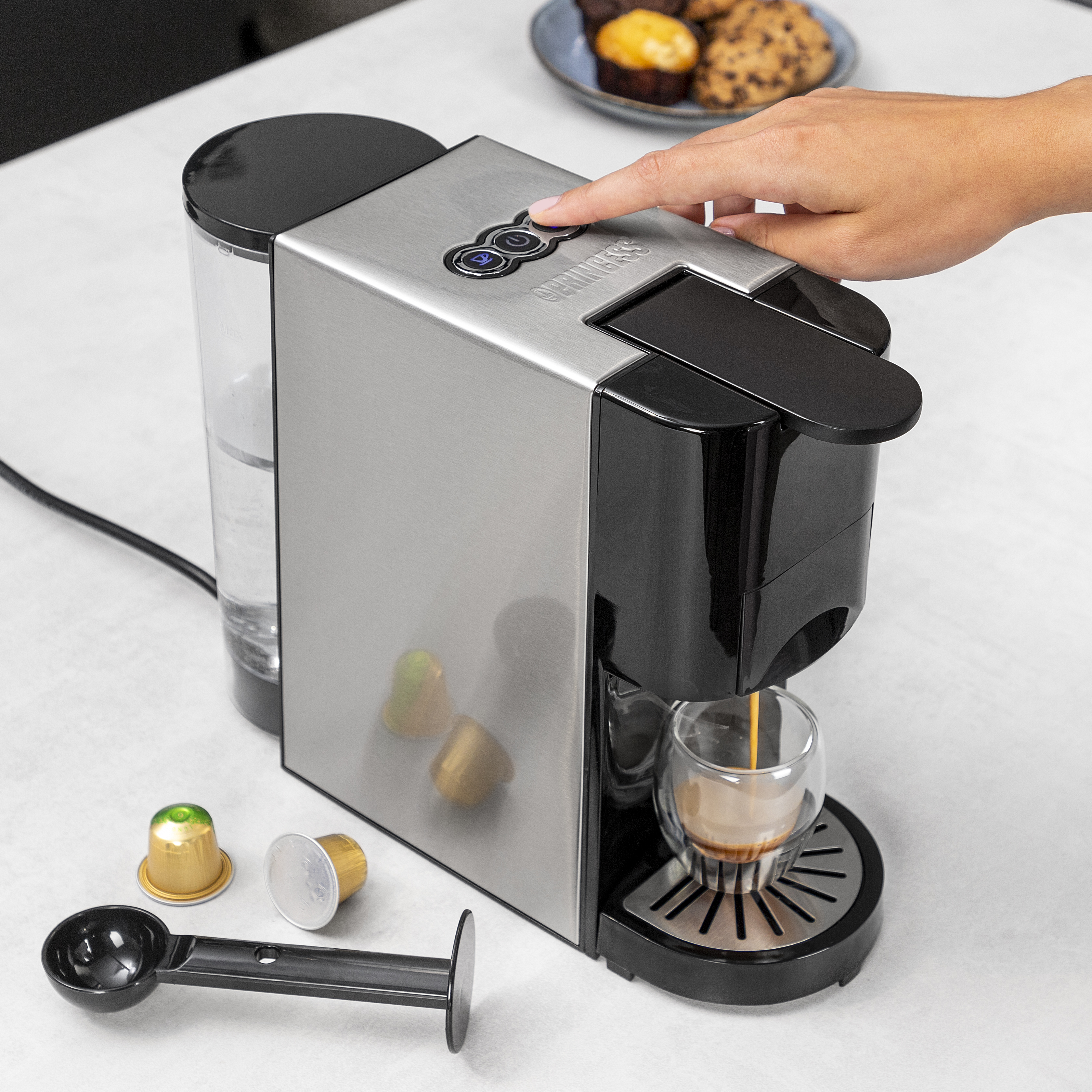 Een persoon die een Princess koffiemachine gebruikt, koffie in een glas giet.