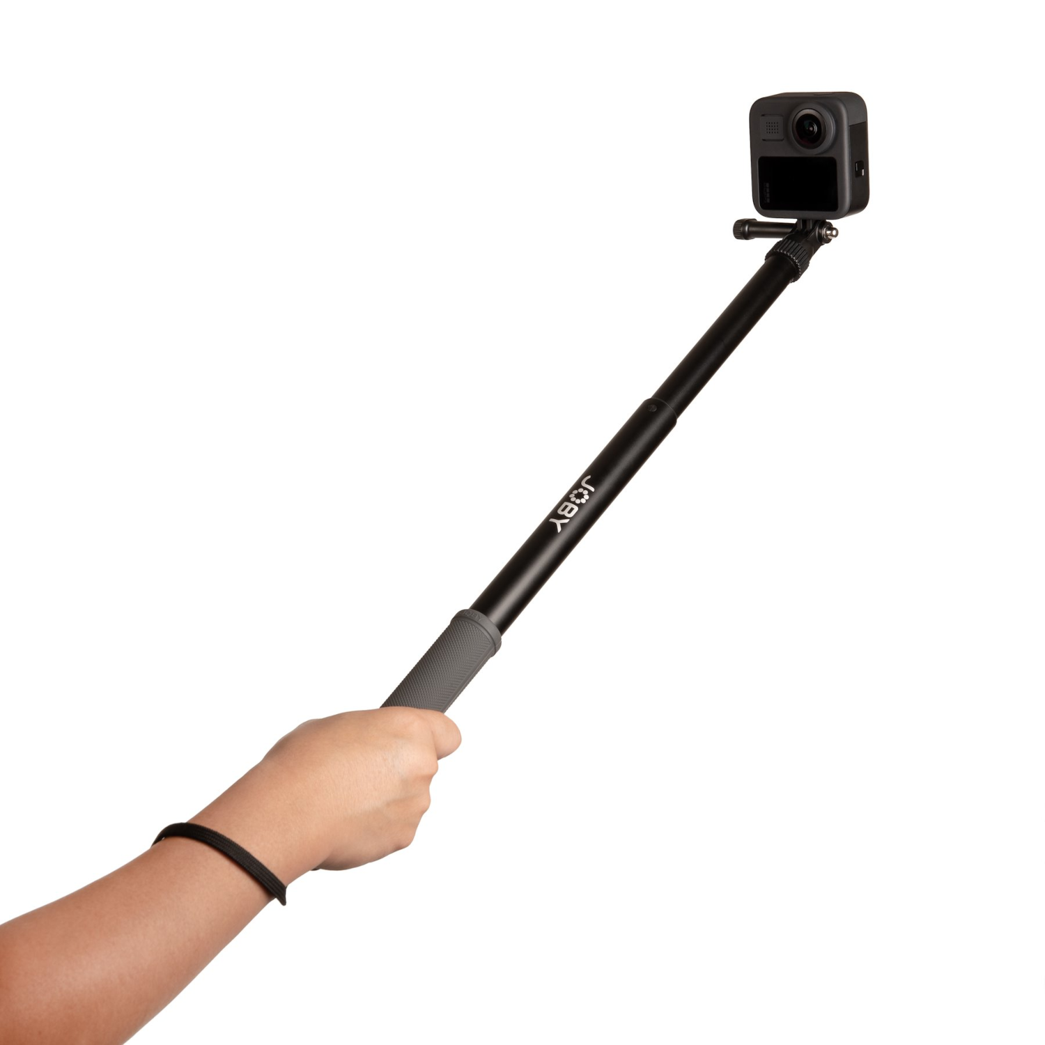 A hand holding a black Joby selfie stick with a black camera on the top, against a white backdrop.