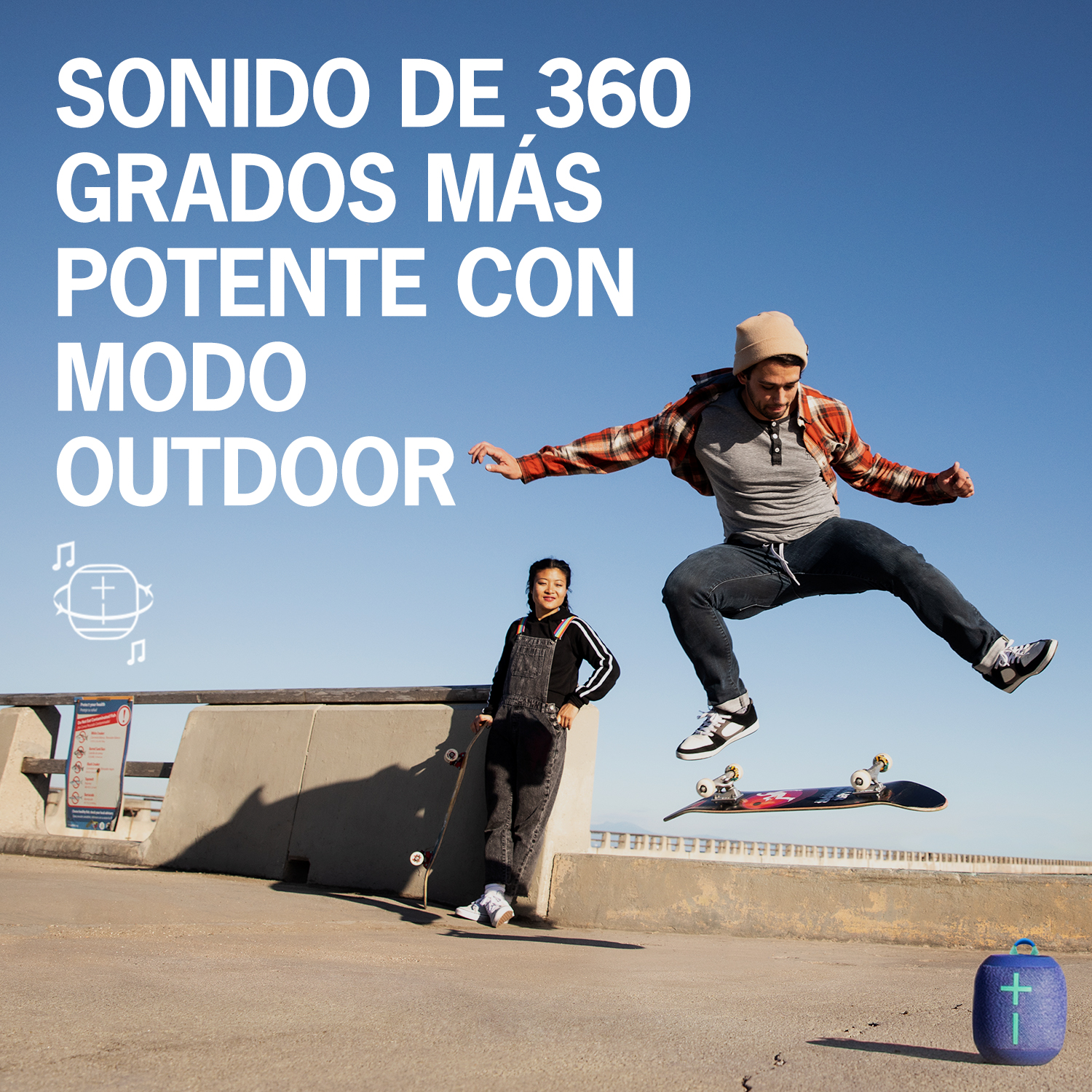 Dos personas con monopatines, uno saltando. Un altavoz está en el suelo.