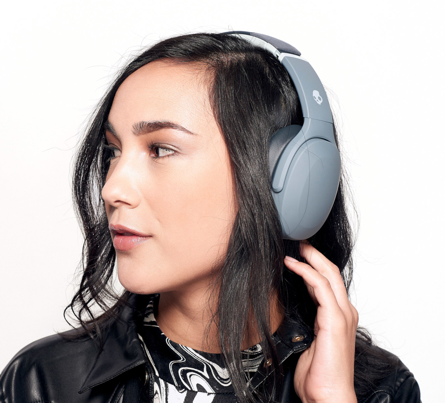 Woman wearing gray headphones, looking to the side. White background.
