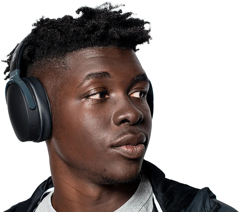 Un jeune homme noir portant un casque foncé, regardant vers la droite, sur fond blanc.