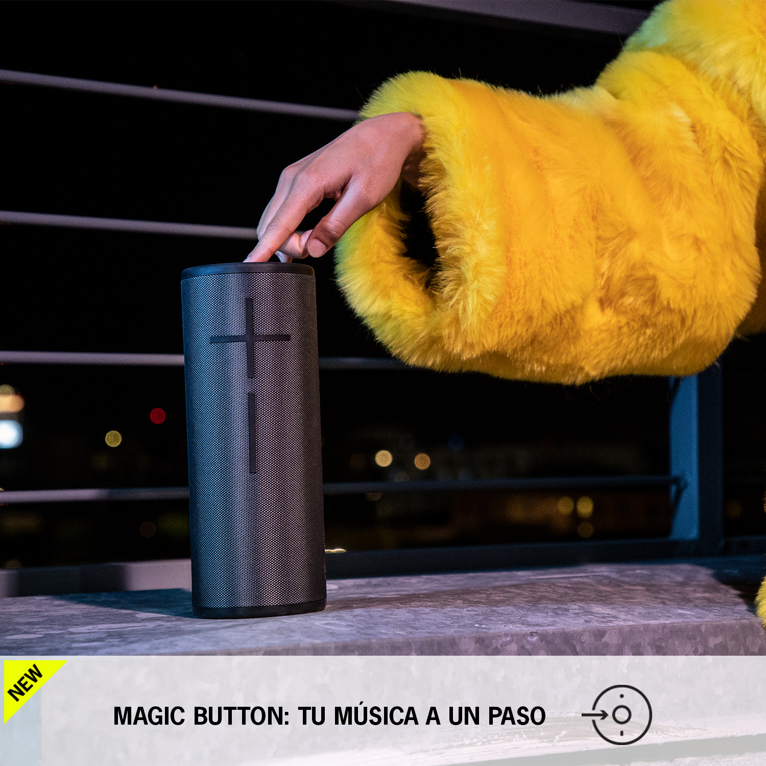 La mano de una persona tocando un altavoz negro con una cruz blanca.