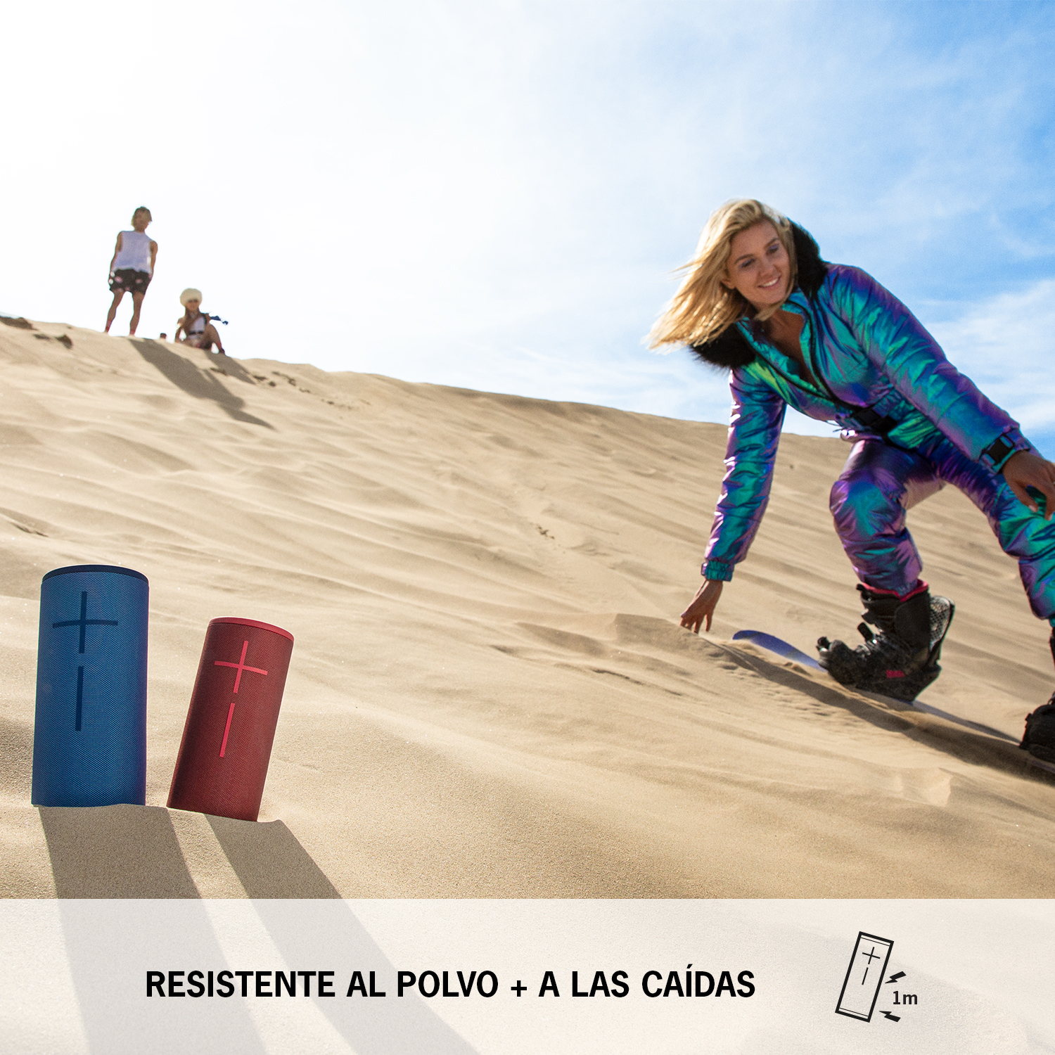 Persona practicando snowboard en una duna de arena con dos altavoces en primer plano.