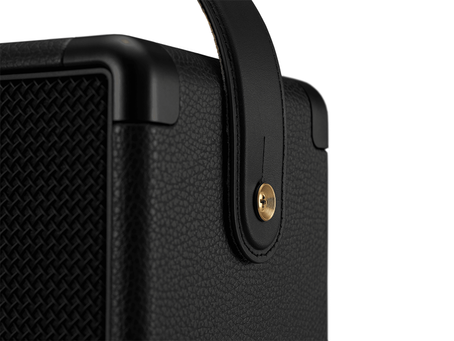 Close-up of black speaker with a leather handle and metallic accents.