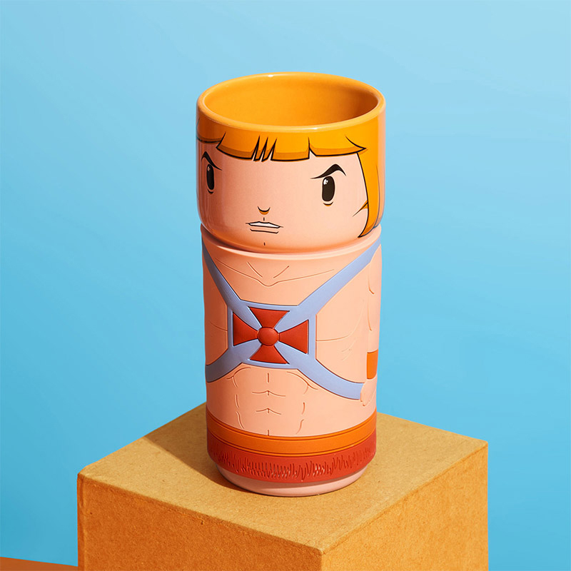 He-Man-Tasse. Oranger Oberteil, Gesichtsdesign. Blauer und roter Torso auf braunem Quadrat.