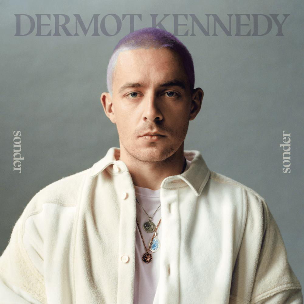 Albumcover: Dermot Kennedy mit lila Haaren, trägt eine weiße Jacke und Halsketten. Text: sonder.