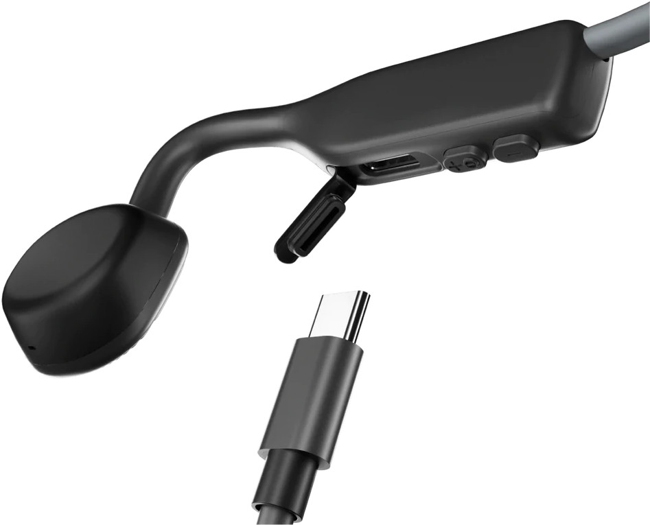 Gros plan sur un casque à conduction osseuse, montrant le port de charge et un câble USB-C pour le chargement.