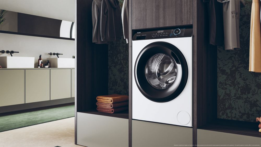 Wasmachine in een badkamer. Handdoeken, kasten en een groen tapijt zijn zichtbaar.