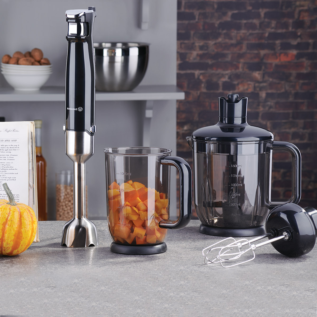 Doğranmış havuç ve siyah beher içeren el blenderi.