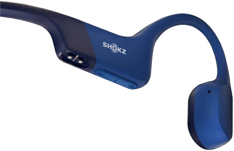Blauwe botgeleidingshoofdtelefoon. De koptelefoon omsluit het oor en hoofd. De merknaam is zichtbaar.