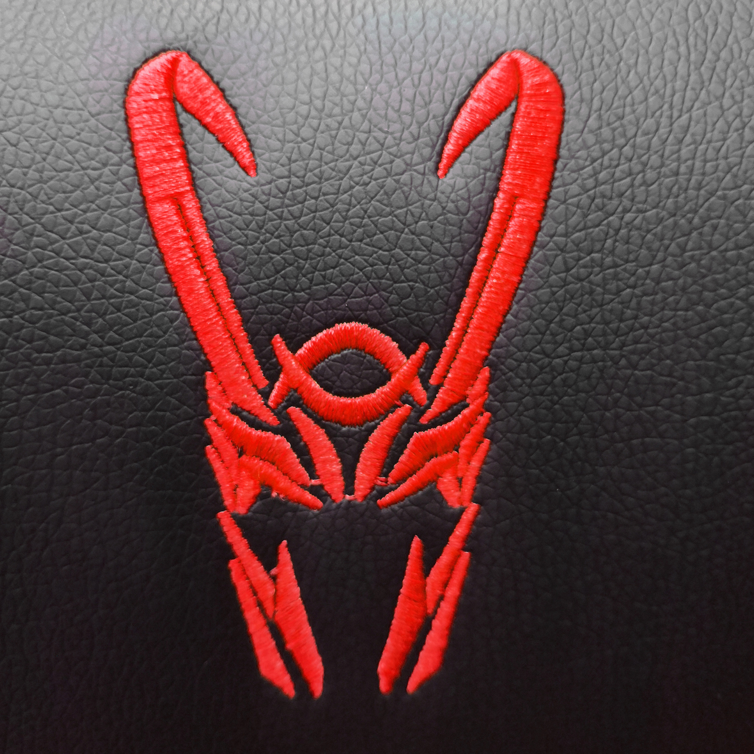 Primer plano de una superficie negra con un símbolo de Loki rojo bordado. El símbolo es un diseño con cuernos.