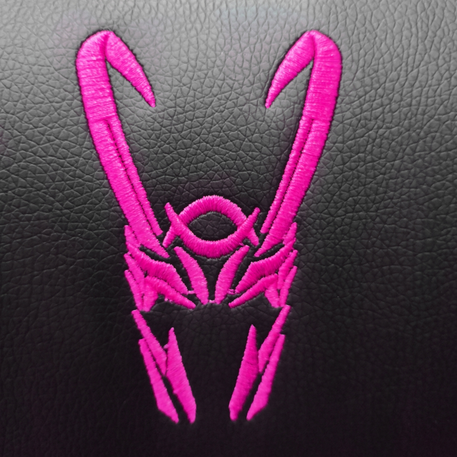 Un logotipo de casco de Loki rosa bordado en una superficie negra.