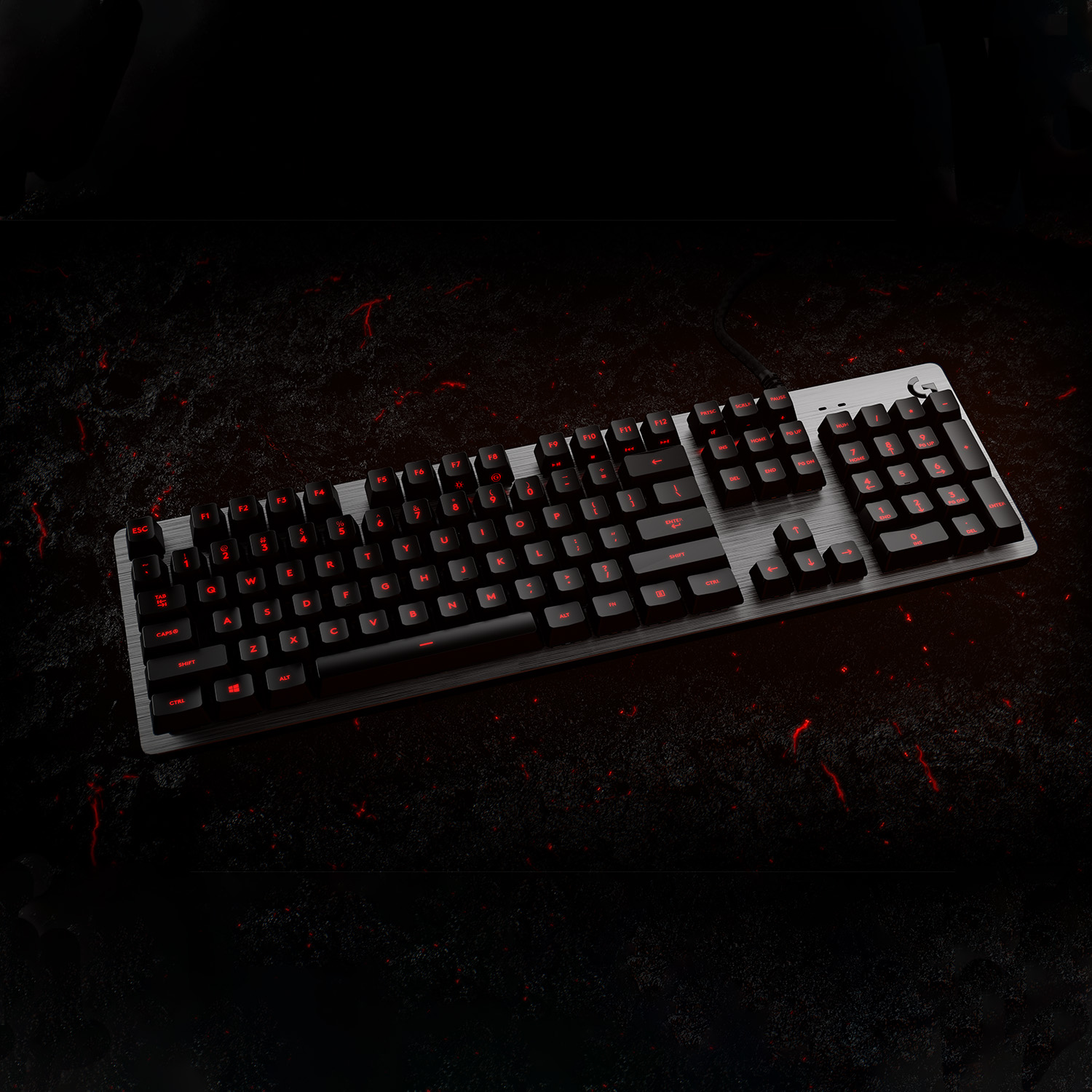 Un teclado gaming negro con teclas retroiluminadas en rojo sobre una superficie texturizada. Ambiente oscuro.