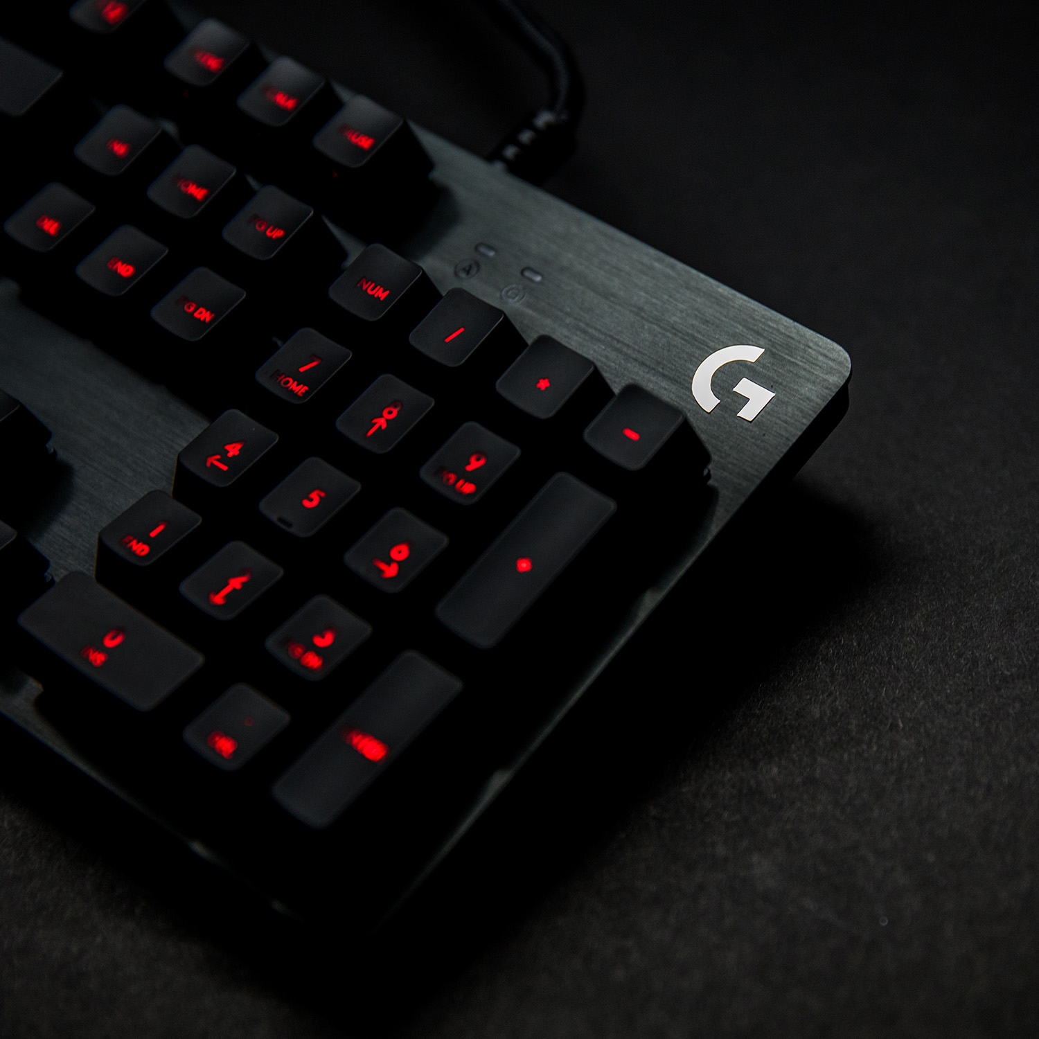 Primer plano de un teclado negro con teclas rojas iluminadas y la letra G.