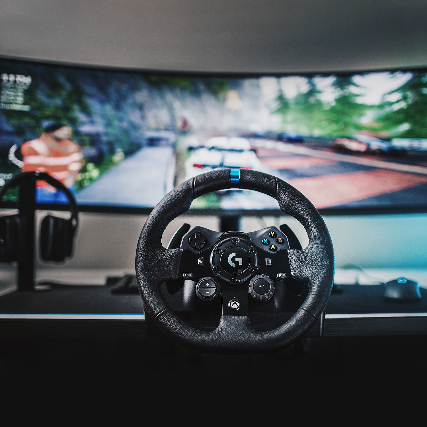 Volante, pantalla de juego, juego de carreras, auriculares, ratón.