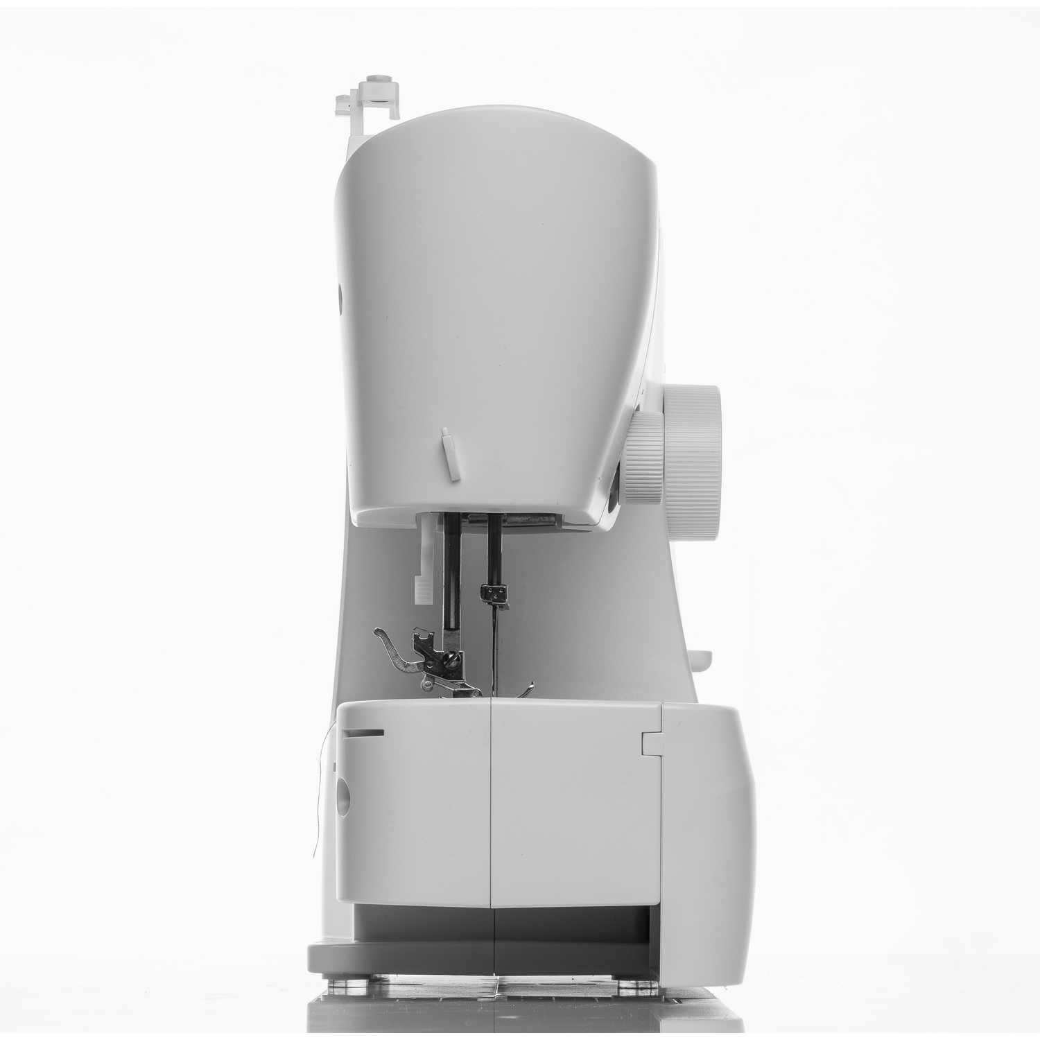 Una máquina de coser blanca, vista lateral. La máquina está sobre una superficie blanca. Fondo blanco.